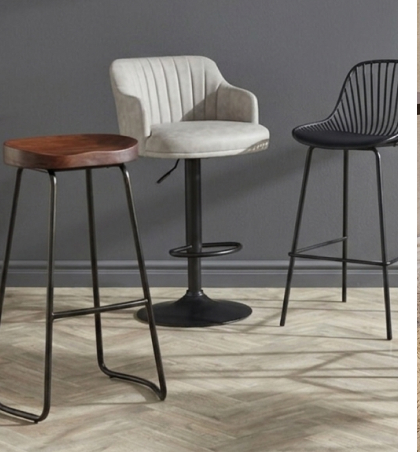 Industrial-style bar stools with black metal frames and tan faux leather padded seats.
