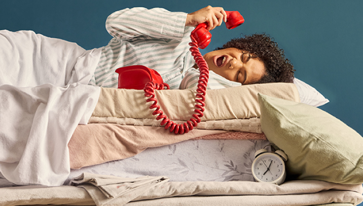 lady with red phone on a pile of sheets and pillows