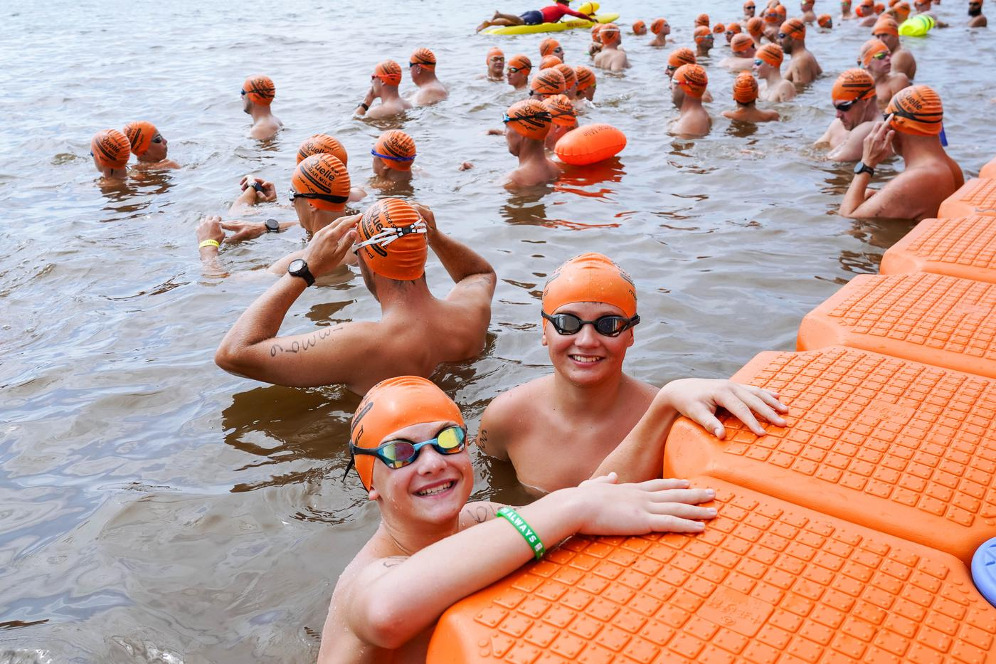 Young swimmers in orange caps and goggles waiting in the water at Midmar Dam